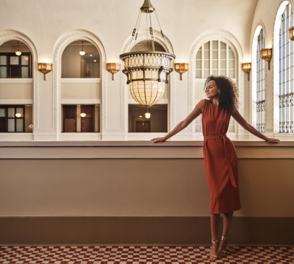 A woman in a red dress standing in the hallway of the Crawford Hotel