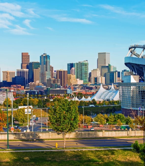 The outside of the Empower Field at Mile High in Denver, Colorado with the city skyline in the background.