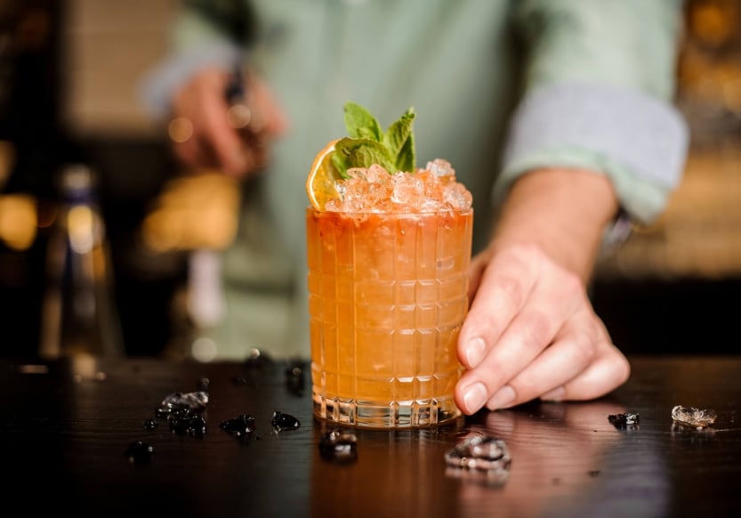 A cocktail with garnish being presented at the bar at Death & Co Denver in Denver, Colorado.