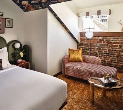 Bed and chaise lounge in the Superior Loft Guest Room at the Crawford Hotel in Denver, Colorado.