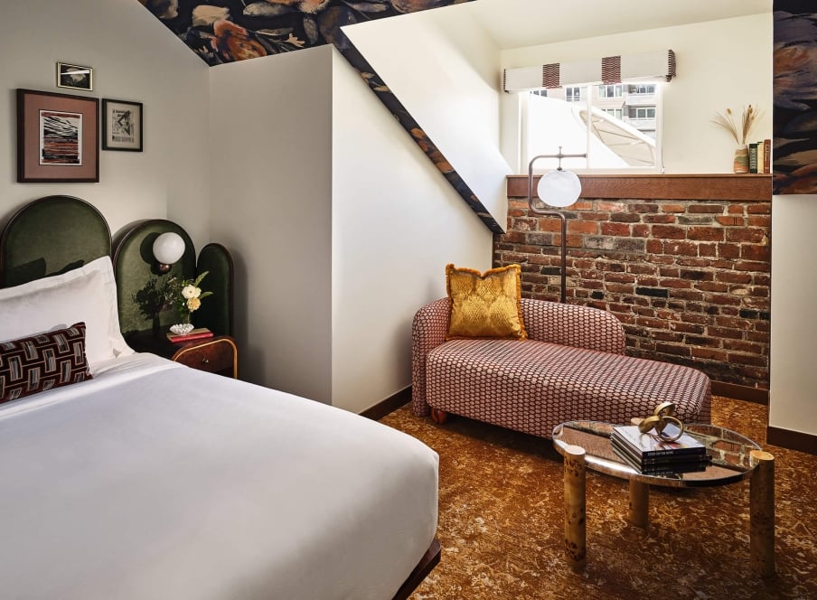 Bed and chaise lounge in the Superior Loft Guest Room at the Crawford Hotel in Denver, Colorado.