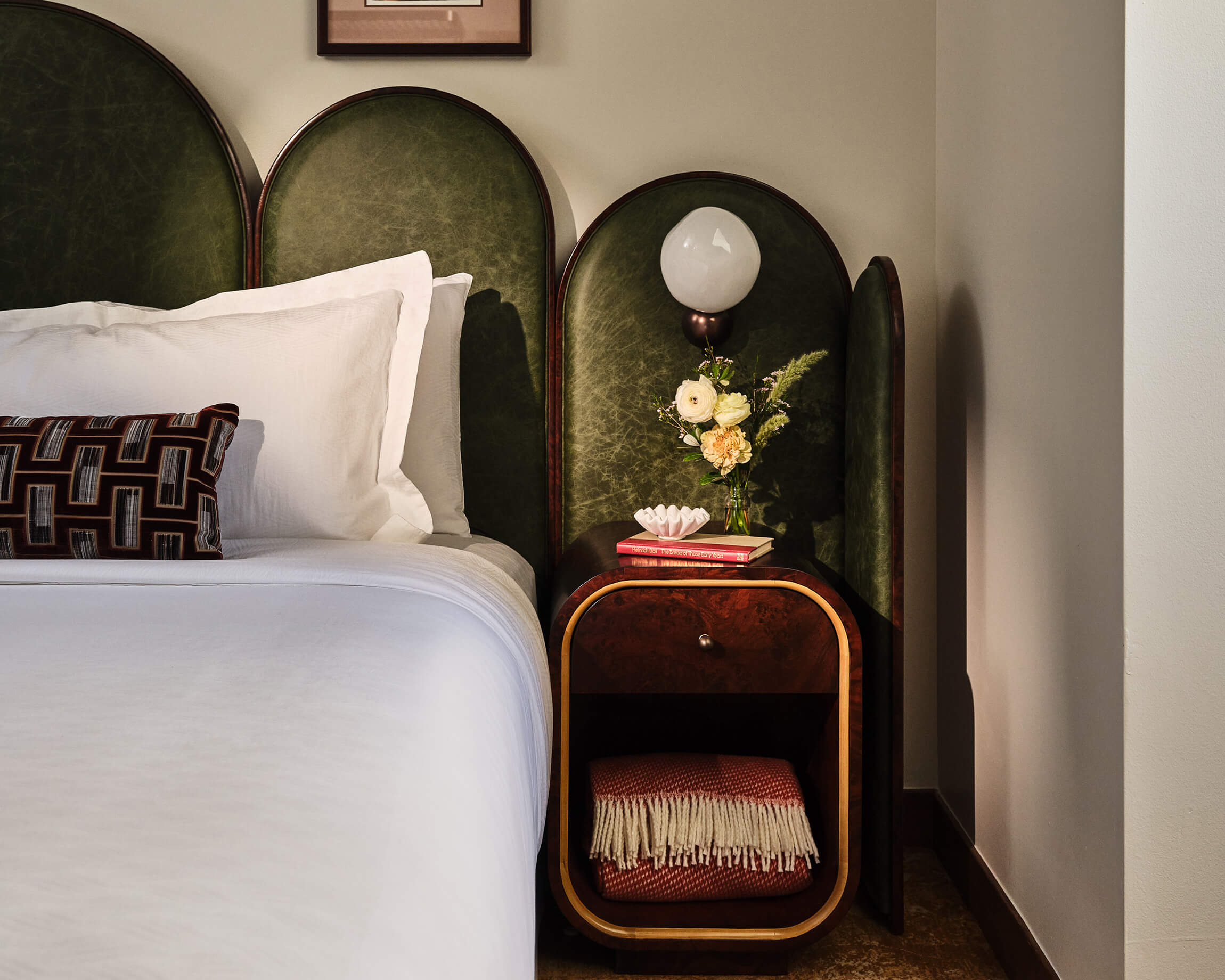 Bedside area with a lamp, side table with extra blanket and fresh cut flowers in the Superior Loft Guest Room at the Crawford Hotel in Denver, Colorado.