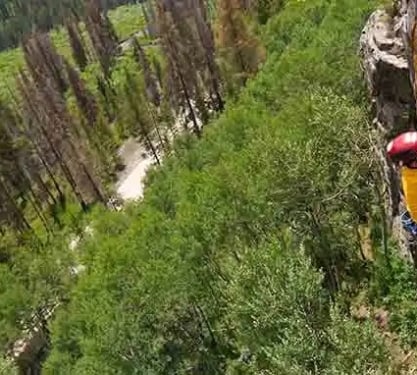 A man rock climbing up a straight rock wall.