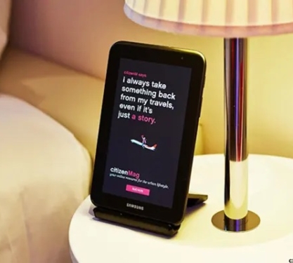 A Samsung tablet on the bedside table in a hotel room.