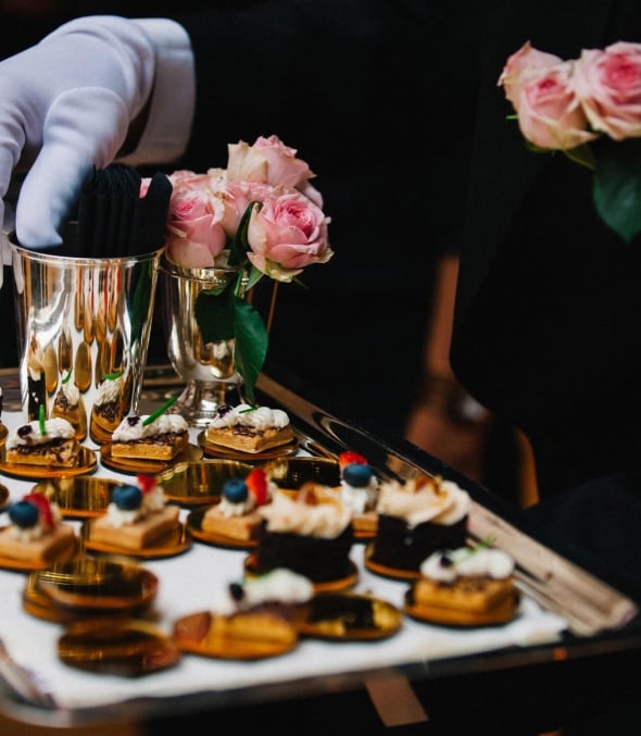A server sets out a silver platter of desserts.