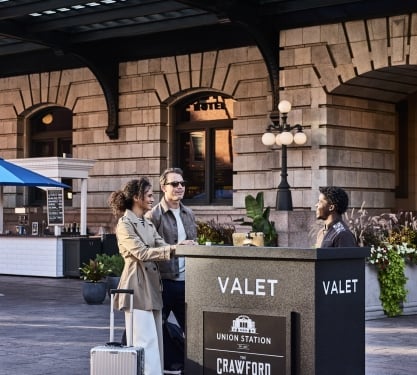 a man nd woman speaking to a valet worker outside denver union station