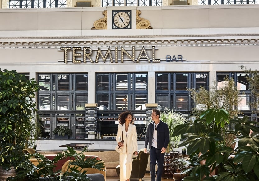 a man and woman walking through denver union station on a sunny day