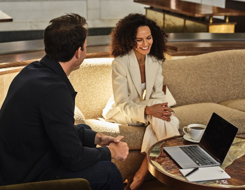 A man and woman sitting and chatting infront of a laptop