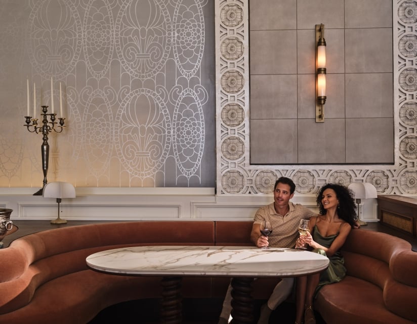 a man and woman enjoying glasses of wine sitting in a booth