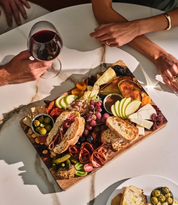 A man and woman sitting at a table enjoying a charcuterie board