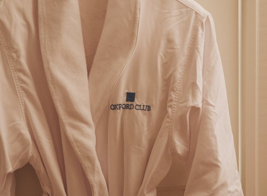 A robe hanging on a door with the Oxford Club logo