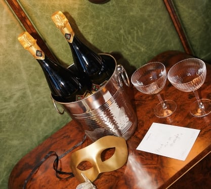 Two Masquerade masks sitting on a table with champagne and glasses