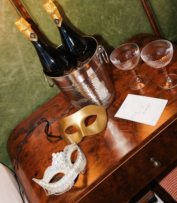 Two Masquerade masks sitting on a table with champagne and glasses