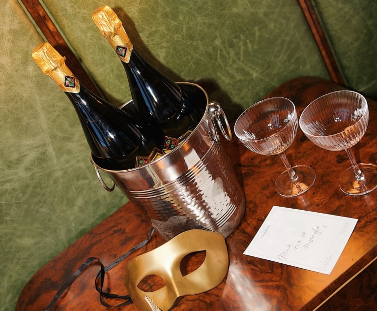 Two Masquerade masks sitting on a table with champagne and glasses