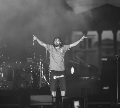 J Cole standing on stage giving a concert